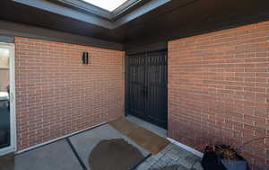 Doorway to property featuring brick siding