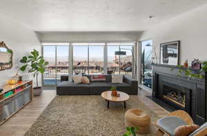 Living room with a fireplace with flush hearth, light wood-type flooring, and a textured ceiling