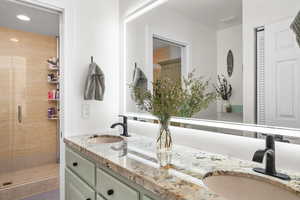 Full bathroom with double vanity, a stall shower, a sink, and recessed lighting