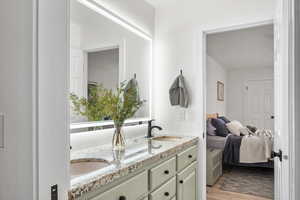 Bathroom with ensuite bathroom, double vanity, wood finished floors, and a sink