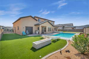 Rear view of house featuring a yard, a patio, stucco siding, an attached garage, and a fenced backyard