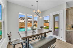 Dining area with baseboards, an inviting chandelier, visible vents, and light wood-style floors