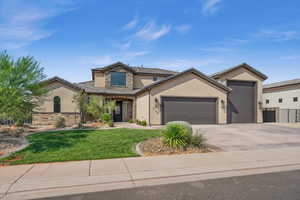 View of front of house featuring stone siding, a front lawn, an attached garage, and stucco siding