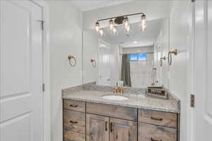 Full bathroom with curtained shower and vanity