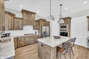 Kitchen with light wood finished floors, stainless steel appliances, decorative backsplash, a sink, and a kitchen island