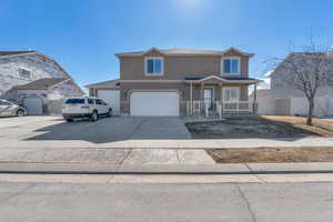 Traditional home featuring driveway, a garage, fence, a porch, and stucco siding