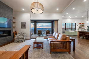 Living area with recessed lighting, wood finished floors, a large fireplace, and an inviting chandelier