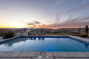 Pool at dusk with fence, a mountain view, and a fenced in pool