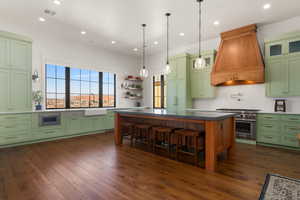 Kitchen with visible vents, high end stainless steel range oven, premium range hood, green cabinets, and backsplash