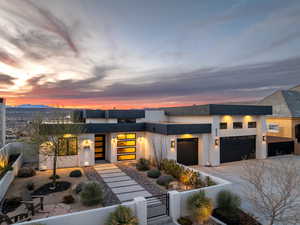 Modern home featuring a garage, driveway, a fenced front yard, a gate, and stucco siding