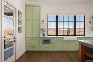 Kitchen with dark wood-type flooring, green cabinets, a sink, and oven