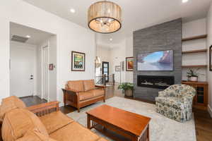 Living room featuring a chandelier, a fireplace, wood finished floors, and visible vents