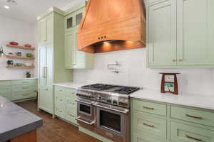 Kitchen with range with two ovens, green cabinets, custom exhaust hood, and tasteful backsplash