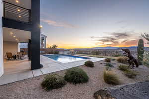 Pool at dusk with a fenced backyard, a mountain view, a fenced in pool, and a patio