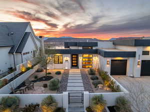 Contemporary house featuring a garage, driveway, a fenced front yard, and stucco siding