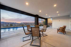 Patio terrace at dusk featuring outdoor dining area and a fenced in pool