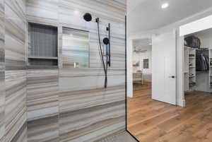 Bathroom featuring a walk in shower, ceiling fan, and wood-type flooring