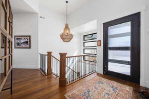 Entrance foyer featuring a chandelier, wood-type flooring, visible vents, and baseboards