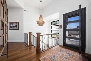 Foyer entrance featuring baseboards, wood-type flooring, visible vents, and an inviting chandelier