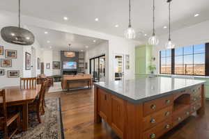 Kitchen featuring recessed lighting, a large fireplace, a kitchen island, brown cabinetry, and dark wood finished floors