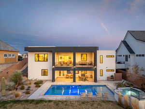 Rear view of house featuring a patio, a balcony, a fenced backyard, an in ground hot tub, and stucco siding