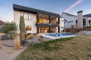 Rear view of house featuring a lawn, a fenced in pool, a balcony, a patio, and stucco siding