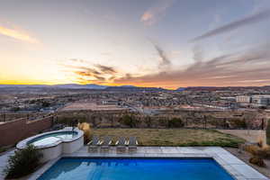 Pool at dusk with a pool with connected hot tub, fence, a mountain view, and a patio