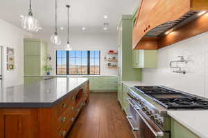 Kitchen featuring range with two ovens, visible vents, custom exhaust hood, and green cabinets