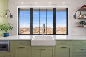 Kitchen with stainless steel oven, a sink, green cabinets, and open shelves