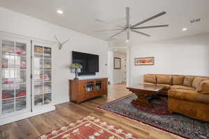 Living room with recessed lighting, visible vents, ceiling fan, and wood finished floors