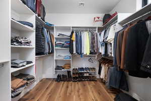 Walk in closet featuring visible vents and wood finished floors