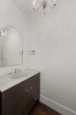 Bathroom with a chandelier, wood finished floors, vanity, and baseboards