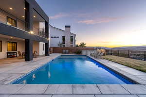 Pool at dusk with a patio area, a fenced backyard, and a fenced in pool