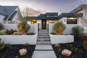 Exterior entry at dusk featuring a gate, fence, and stucco siding