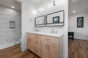 Bathroom with toilet, double vanity, a sink, and wood finished floors