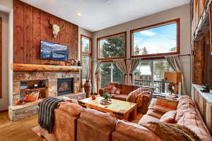 Living area with wood walls, a fireplace, a high ceiling, and wood finished floors