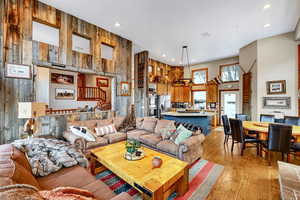 Living room featuring light wood-type flooring, wooden walls, a high ceiling, and recessed lighting