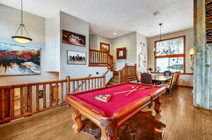 Game room featuring wood-type flooring, a notable chandelier, billiards, and baseboards