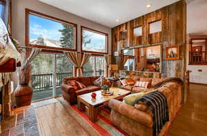 Living room with wooden walls, recessed lighting, a towering ceiling, and wood finished floors