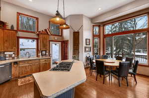 Kitchen with hardwood / wood-style flooring, a sink, gas stovetop, brown cabinets, and dishwasher