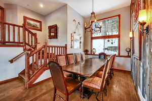 Dining room with baseboards, wood finished floors, stairs, a notable chandelier, and recessed lighting