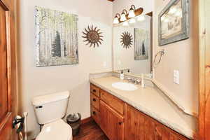 Bathroom featuring vanity, wood finished floors, toilet, and baseboards