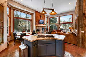 Kitchen featuring gray cabinetry, stainless steel gas cooktop, a fireplace, light countertops, and dark wood-style floors