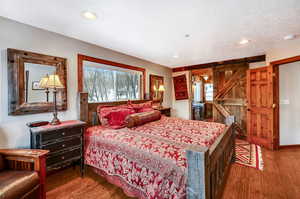 Bedroom featuring a barn door, a textured ceiling, wood finished floors, and recessed lighting