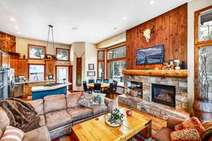 Living area with a fireplace, recessed lighting, a towering ceiling, wood walls, and wood finished floors