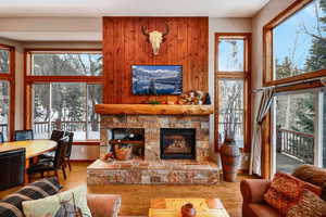 Living area featuring a wealth of natural light, a stone fireplace, a towering ceiling, and wood finished floors