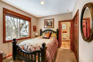 Bedroom with a textured ceiling, light carpet, and baseboards