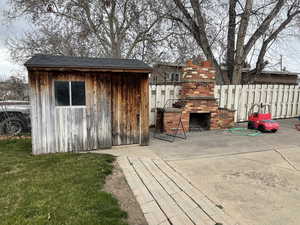 View of shed featuring a fireplace and fence