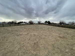 View of yard with an enclosed area, a rural view, and fence