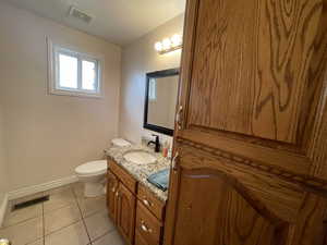 Bathroom with visible vents, vanity, toilet, and tile patterned floors